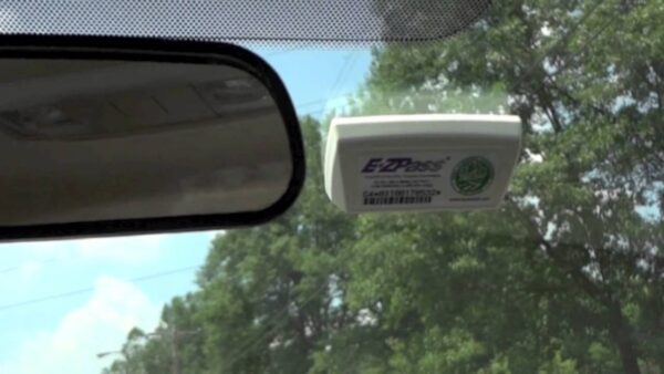 close-up of e-zpass transponder with velcro strips attached to a car windshield for easy mounting.