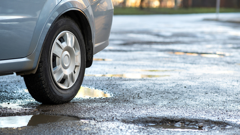 When a tyre bumps into a pothole, it can experience tread separation or sidewall bulges car on road with potholes